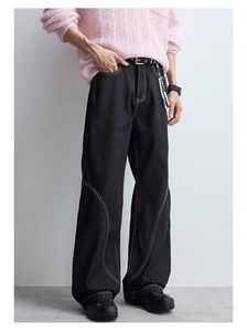 Détail d'un jean en denim noir ample avec surpiqûres blanches et lignes structurées