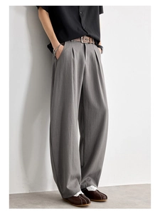 Détail du pantalon large gris montrant les plis à la taille et la texture du tissu