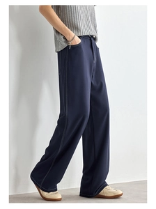 Dettaglio dei pantaloni larghi blu scuro con cuciture bianche a contrasto e drappeggio
