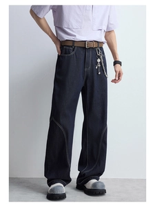 Détail d'un jean large bleu foncé avec surpiqûres blanches contrastées sur denim épais