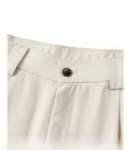 Detail of beige textured pants waist with button, elastic band, and belt loops