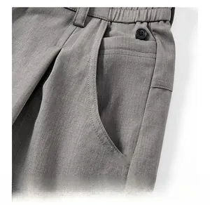 Détail macro du pantalon décontracté gris avec taille plissée et poche boutonnée