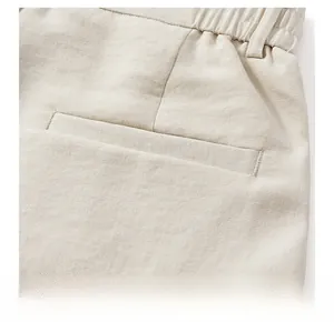 Detail showing back pocket design and textured fabric of beige casual trousers