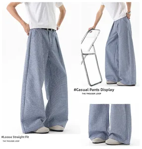 Détail du pantalon large à carreaux bleu et blanc avec une ceinture noire minimaliste