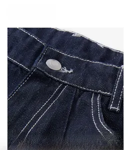 Détail de la taille du jean bleu foncé avec bouton argenté et surpiqûres blanches contrastées