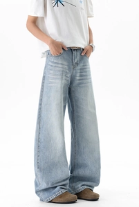 Detail view of washed light blue denim jeans with cat-whisker texture and wide-leg fit