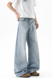 Detail of light blue baggy jeans with vintage wash and distinct whisker creases
