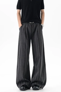 Detail of dark grey striped wide-leg pants showing premium fabric texture and front pleats