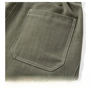 Dettaglio dei pantaloni sportivi verde militare con tasca posteriore e cuciture bianche