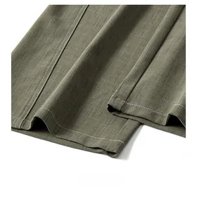 Dettaglio dell'orlo dei pantaloni verde militare con cuciture bianche a contrasto e trama