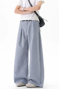 Détail du pantalon large à carreaux bleus montrant le drapé et la taille plissée