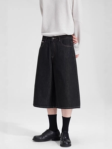 Men's loose black denim shorts with white contrast stitching and wide leg cut
