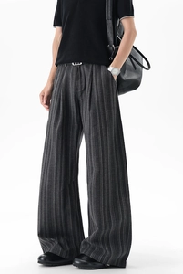 Close-up of dark grey pinstripe wide-leg trousers showing drape and waist pleat details