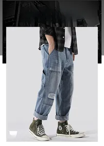 Detail view of light blue washed patchwork denim jeans with distressed ripped effects