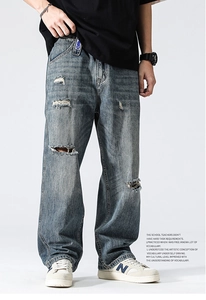 Gros plan sur la texture denim usée et les détails déchirés du jean bleu pour hommes