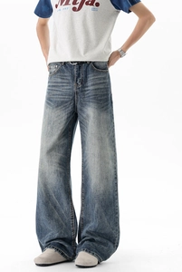 Detail of vintage washed blue wide-leg jeans featuring whiskers and distressed texture