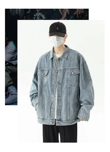 Detail of light blue oversized denim jacket featuring metal buttons and chest pockets
