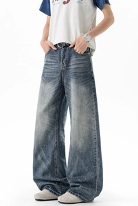 Detailed view of the washed denim fabric with vintage cat scratch fades on wide-leg jeans