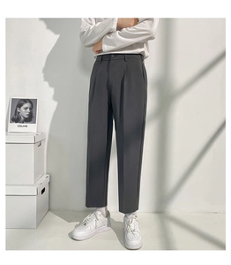Détail d'un pantalon de costume gris foncé à coupe droite avec plis marqués et tissu lisse