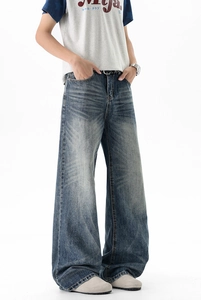 Detail of vintage washed dark blue wide-leg jeans with whiskering and distressed texture