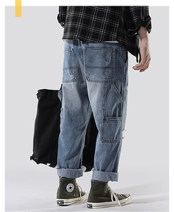 Detail view of men's light blue cargo jeans with large side pockets and washed denim texture
