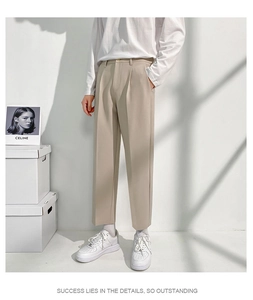 Détail du pantalon droit beige montrant le drapé lisse du tissu et le pli frontal chic