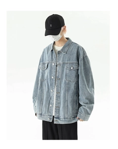 Detail of light blue denim jacket showing flap pockets and vintage wash texture