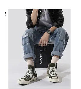 Detailed view of distressed light blue straight jeans styled with high-top green canvas shoes