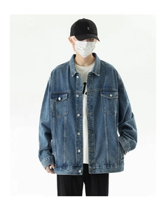 Detail of vintage blue denim jacket with washed texture and chest pockets in a relaxed fit
