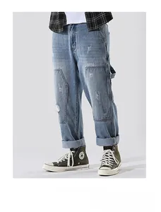 Detail of light blue straight denim jeans featuring vintage distressed holes and cargo pockets