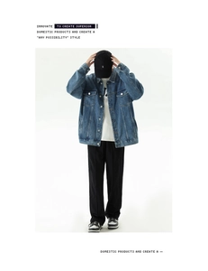 Detail of light blue denim jacket with vintage wash texture and loose fit style