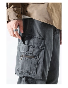 Detail view of charcoal gray work pants showing flap pockets with metal zipper accents