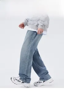 Detail showing loose wide-leg fit and light blue washed denim texture on men's streetwear jeans