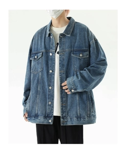 Detail view of mid-blue denim jacket with metal buttons and washed texture finish