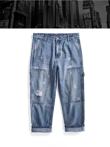 Detail of light wash straight denim jeans with paneled patchwork and distressed effects