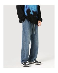 Détail d'un jean bleu à coupe large avec effet délavé et taille élastique à cordon blanc