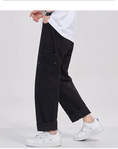 Détail du pantalon cargo noir en coton avec coutures contrastées blanches et grandes poches