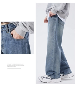 Detail of light blue washed denim jeans showing waist pocket and loose straight leg fit