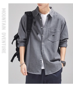 Detail of dark grey brushed cotton shirt featuring a breast pocket and MUBAN embroidery