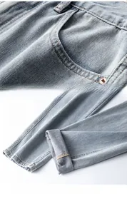 Détail du jean bleu clair montrant les coutures précises et l'ourlet retroussé