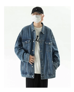 Detailed view of dark blue washed denim jacket with metal buttons and chest pockets