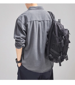 Rear view of a model wearing a grey brushed cotton shirt and a black functional backpack