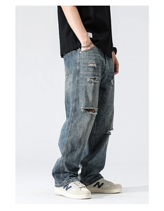 Détail d'un jean bleu vintage avec déchirures usées et coupe large pour hommes