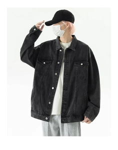 Detail of loose fit black denim jacket featuring metallic buttons and flap chest pockets