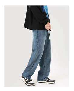 Détail d'un jean bleu délavé ample avec cordon de serrage blanc et coupe droite décontractée