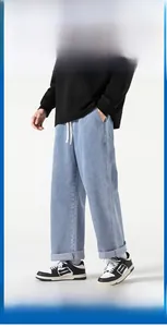 Dettaglio di jeans in denim lavato azzurro con coulisse bianca e taglio a gamba larga