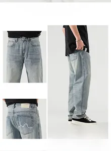Détail d'un jean droit bleu clair avec broderie vague blanche sur la poche arrière