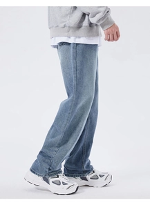 Detail view of baggy straight-leg blue washed denim jeans for men in loose street style