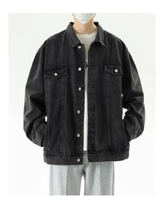 Detail of oversized dark grey washed denim jacket featuring flap chest pockets and buttons
