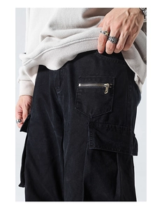 Detail of black utility cargo pants featuring side flap pockets and metal zippers